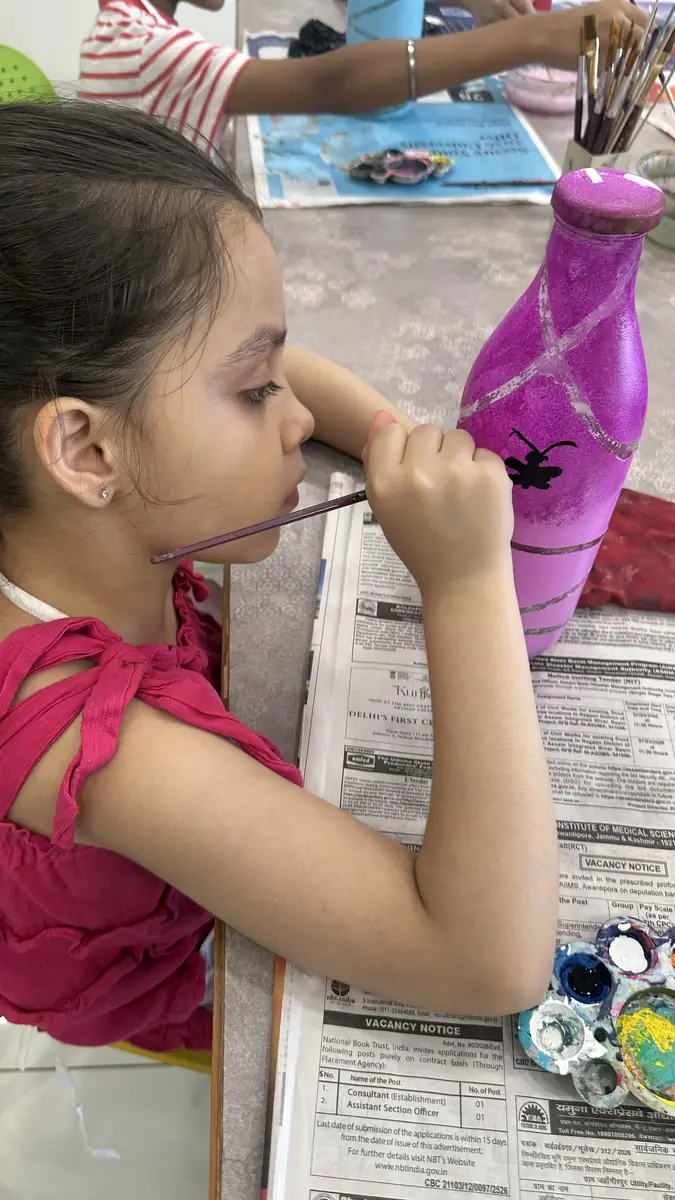 A young painter working carefully on a purple bottle
